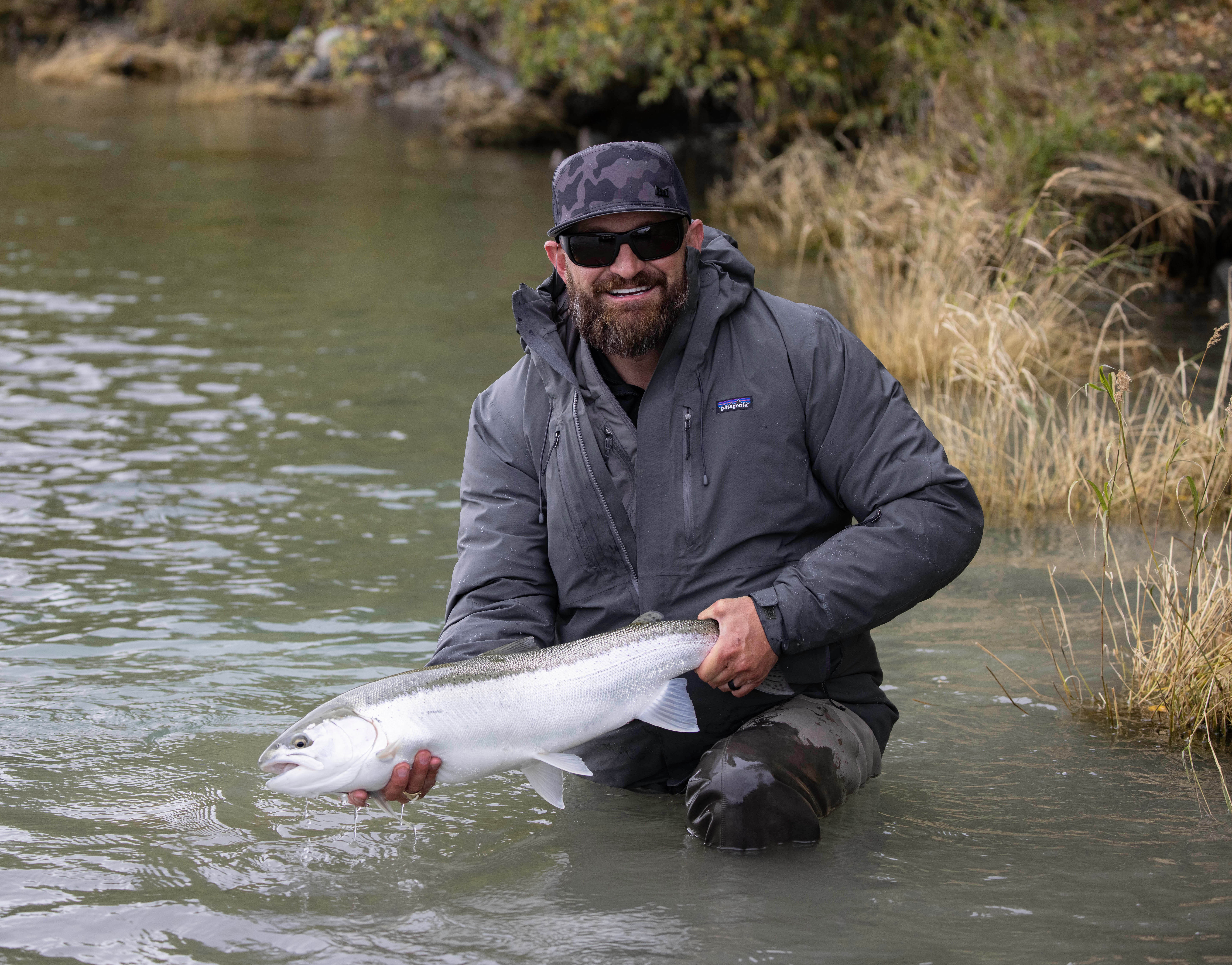 Matt Smith kneeling in a Utah river holding a steelhead — what Teach a Human to Fish is all about